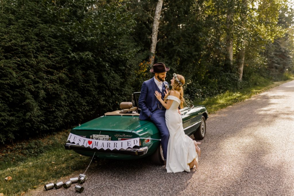 bride and groom leaning up against a classic car
