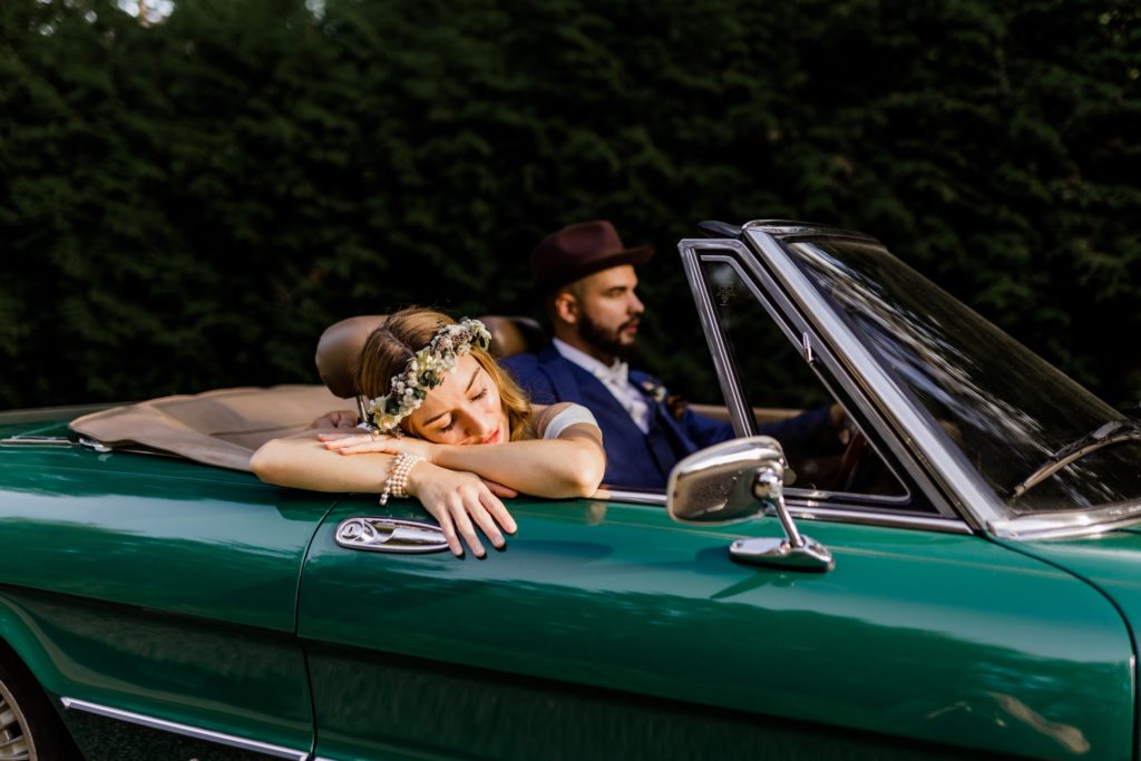 bride resting her head on the classic car